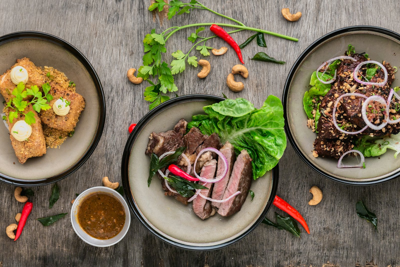 Mesa com vários pratos: carne, salada e acompanhamentos